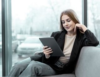 Frau mit ihrem Tablet am Sofa