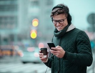 Young man uses his smartphone with coffee in his hand